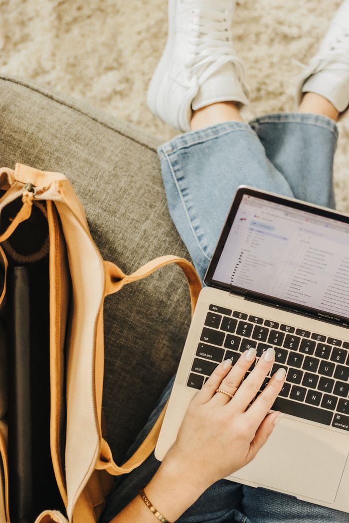who-we-are A person using a laptop with an elegant tote bag nearby in a casual setting.