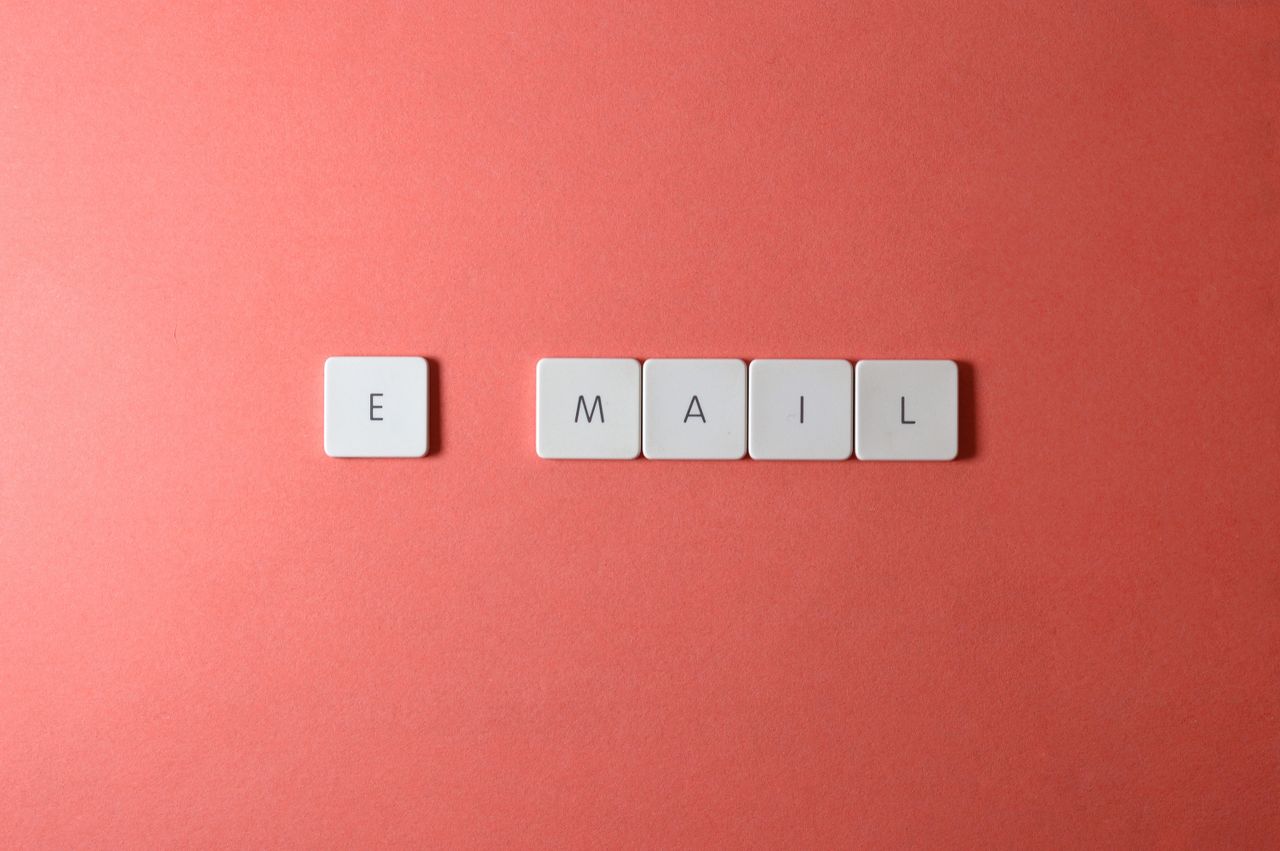 services-04 Flat lay of keyboard letter tiles spelling email on coral backdrop.